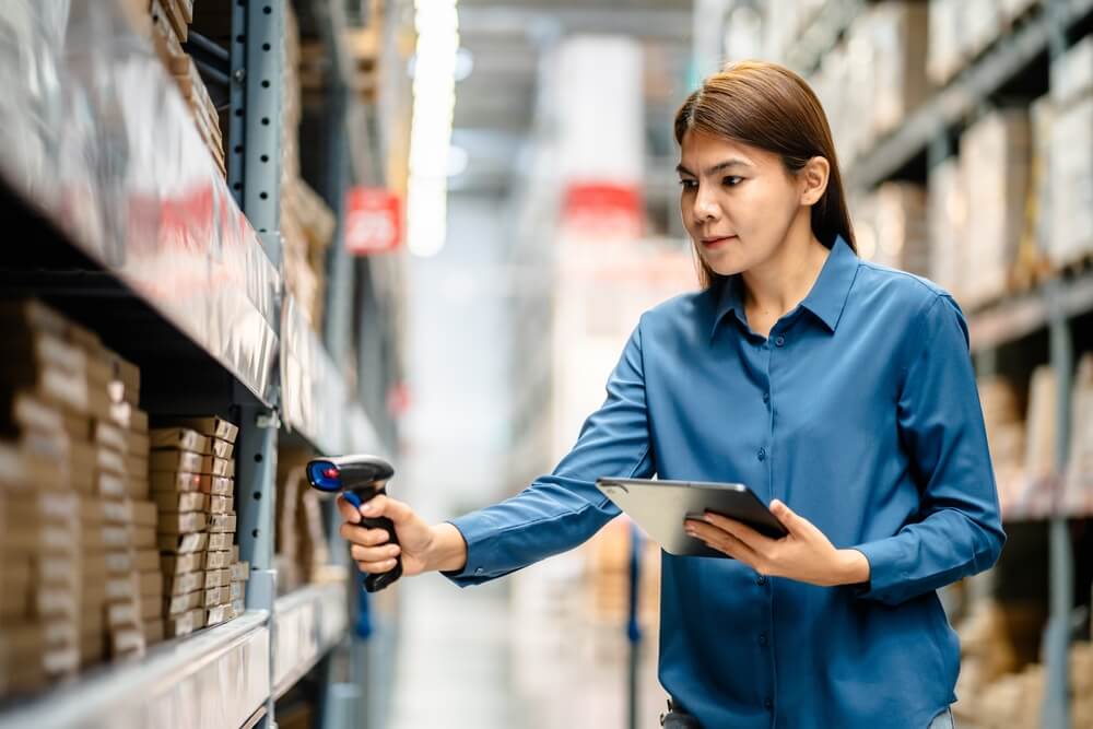 Woman in a blue shirt counting dead stock in a warehouse